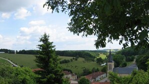 A rural landscape with a church, houses, and open fields.
