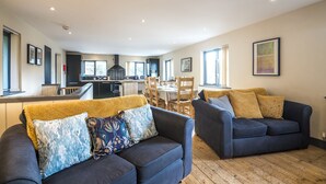 A modern living room with two sofas, a dining area, and a kitchen in the background. - Rock Cottage - 3 Bedroom Holiday Home (Fishguard)