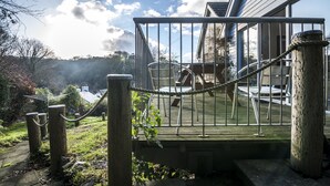 A wooden deck with metal railings, a rope barrier, and outdoor furniture. - Rock Cottage - 3 Bedroom Holiday Home (Fishguard)