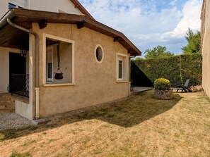 A house with a covered porch, a small window, and a well-maintained lawn.