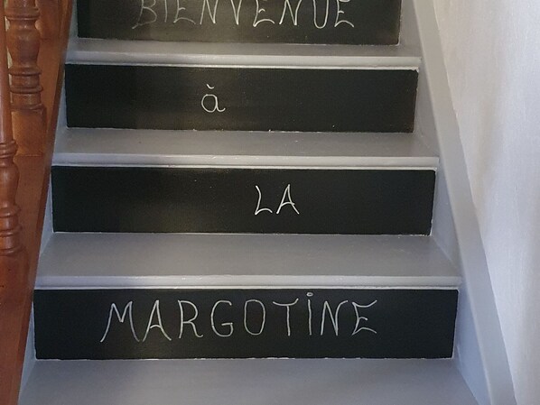 Una escalera con peldaños etiquetados en francés, indicando una bienvenida a 'LA MARGOTINE'.