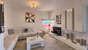 A modern living room with a sofa, coffee table, TV, and artwork.
