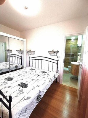 A bedroom with a bed, a mirror, and a bathroom visible through an open door.