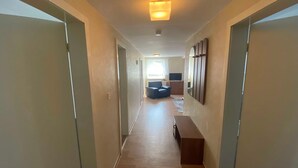 A hallway with a sofa, a television, and a wooden bench.