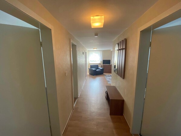A hallway with a sofa, a television, and a wooden bench.