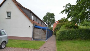 A residential building with a paved pathway, a garage, and a car parked on the side.