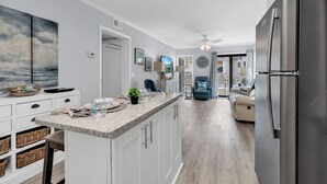 Una cocina moderna con una isla grande, armarios blancos y un refrigerador de acero inoxidable.