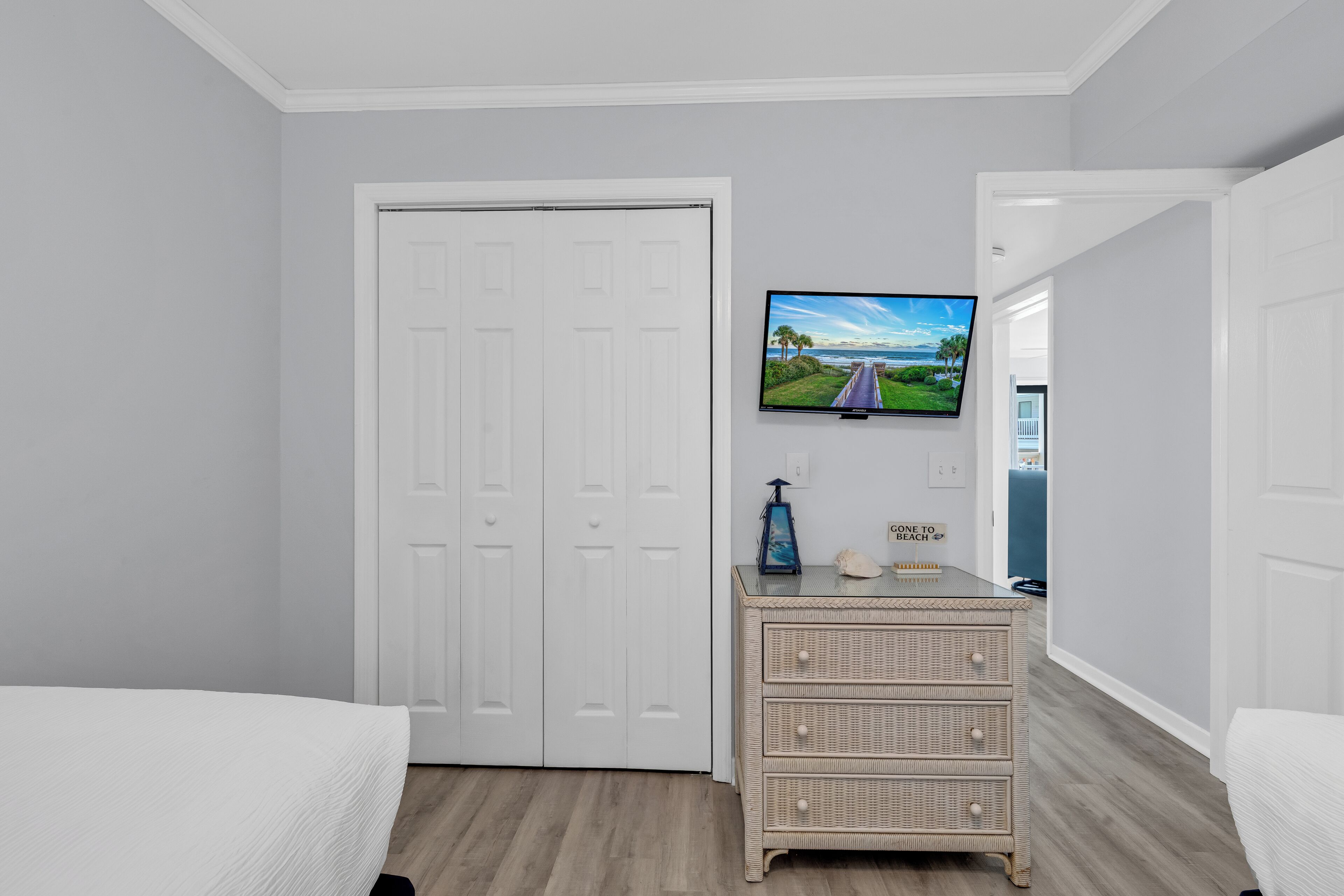 Une chambre à coucher avec un lit, une commode, un téléviseur et une porte.
