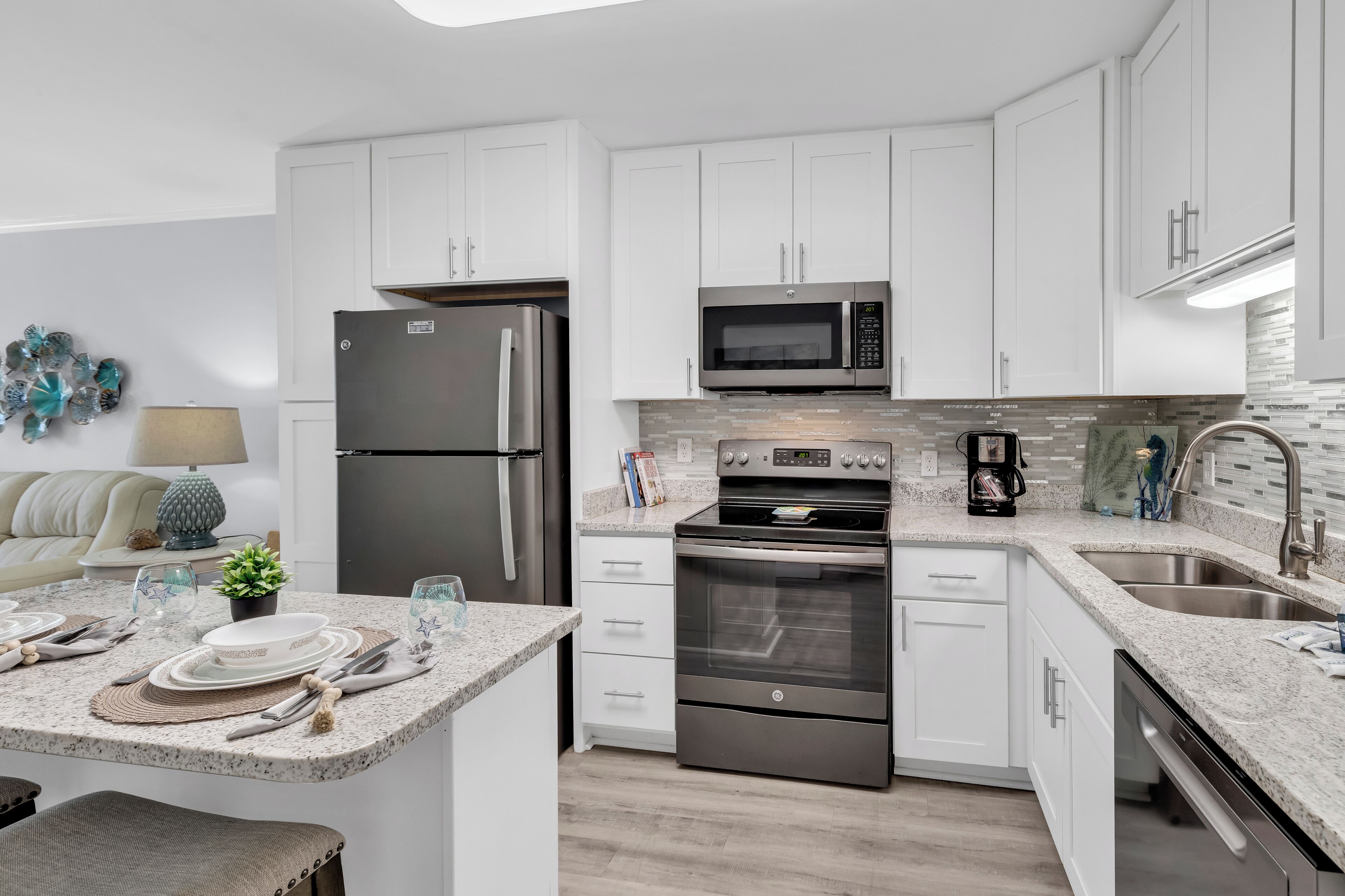 A modern kitchen with white cabinets, stainless steel appliances, a granite countertop, and a built-in oven.