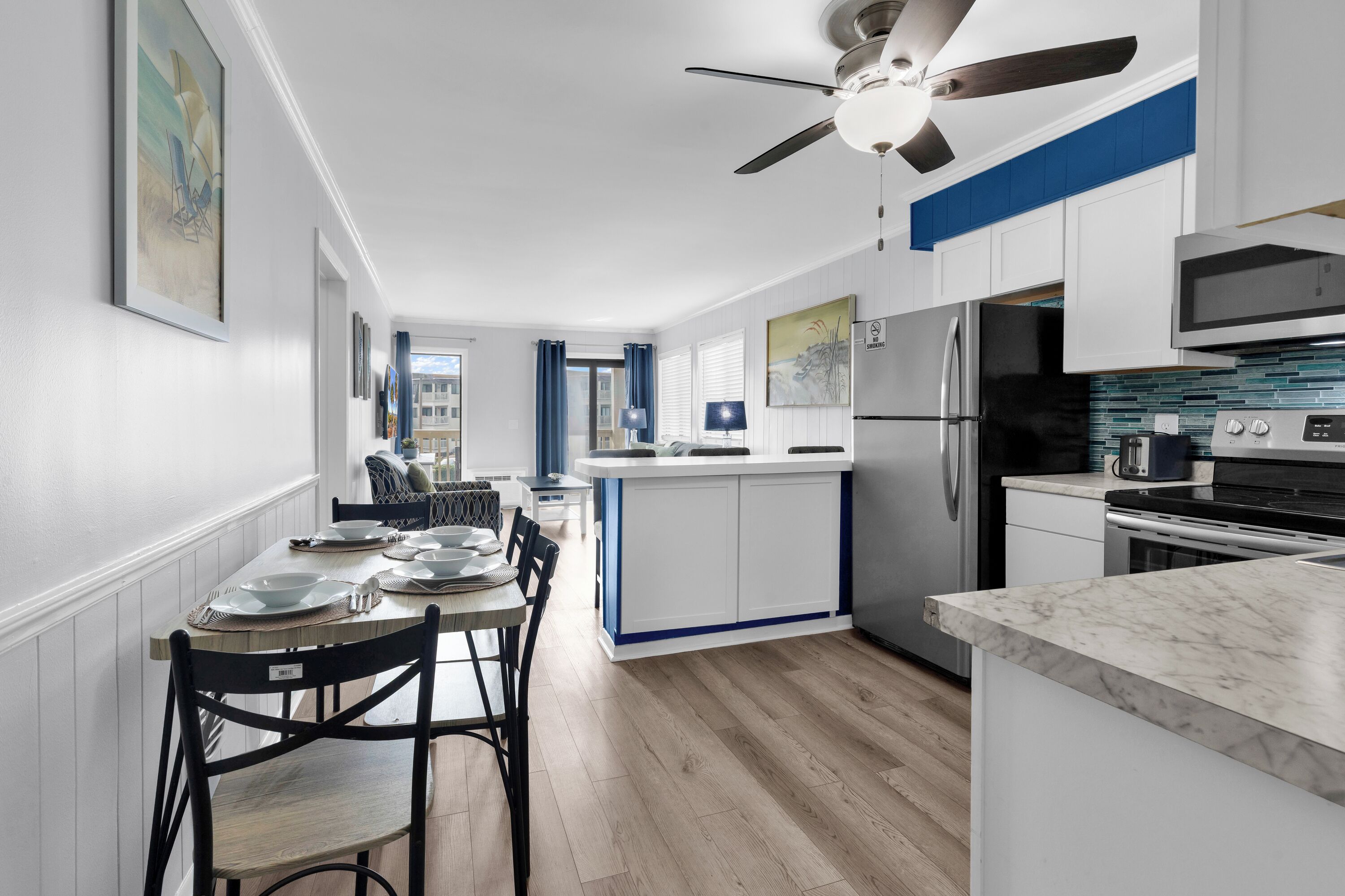 A modern kitchen with white cabinetry, a built-in island, and a stainless steel refrigerator.
