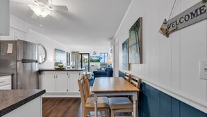 Una cocina moderna con armarios blancos, un refrigerador de acero inoxidable y una mesa de comedor de madera con sillas.