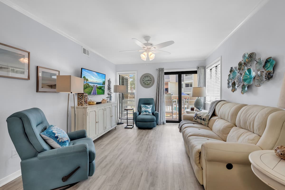 A living room with a sofa, recliner, television, and decorative items.