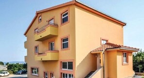 Un immeuble à plusieurs étages, doté d’une façade jaune et d’un toit recouvert de tuiles rouges.