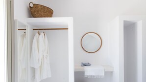 A bathroom with white walls, a wooden towel rack, a mirror, and a shelf with a towel and a basket. - Villa ILI - An Uncompromised luxurious escape  (Naxos)