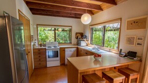 Une cuisine moderne avec des meubles en bois, un four encastré, un réfrigérateur et un grand îlot central doté de tabourets.