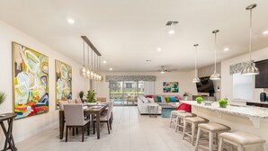 Eine geräumige Küche mit Essbereich, ein Wohnzimmer und ein großes Fenster mit Blick auf einen Garten.