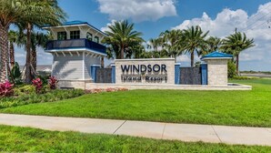 Schild für das Windsor Island Resort mit einem modernen Gebäude und Palmen.
