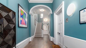 A hallway with teal walls, a wooden floor, a staircase, and a door marked with the number 3. - Charlotte Rise (Bristol)