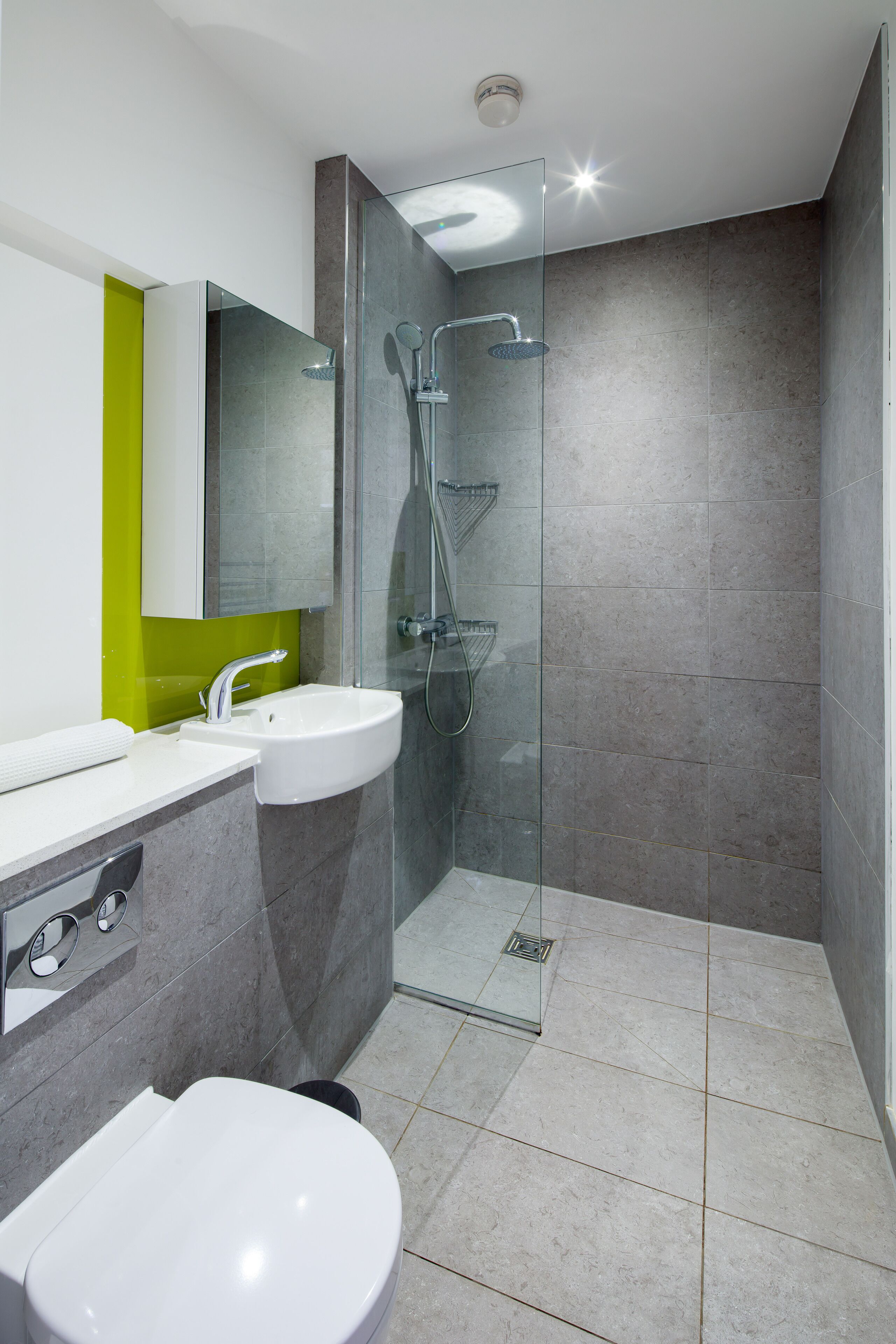 A modern bathroom with a glass-enclosed shower, a white sink, and a toilet.