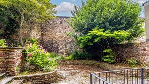 A courtyard with stone walls, a metal railing, and lush greenery. - Charlotte Rise (Bristol)