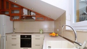 A modern kitchen with white cabinets, a built-in oven, and a stainless steel sink. - Two Bedroom Apartment with Balcony (Kaštel Stari)