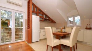 A spacious kitchen with a dining area, wooden cabinets, and a large window. - Two Bedroom Apartment with Balcony (Kaštel Stari)