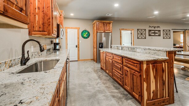 Una cocina con armarios de madera, encimera de granito, electrodomésticos de acero inoxidable y una isla grande.