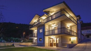 Un edificio residenziale a più piani con balconi, facciata in pietra e ingresso ben illuminato.