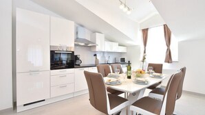 Una cucina moderna con mobili bianchi, un tavolo da pranzo apparecchiato per quattro persone e un lampadario.