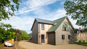 A wooden house with a gravel driveway and a small garden area.