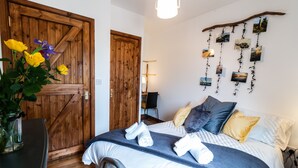 A bedroom with a wooden door, a bed with towels, pillows, and a wall-mounted photo display.