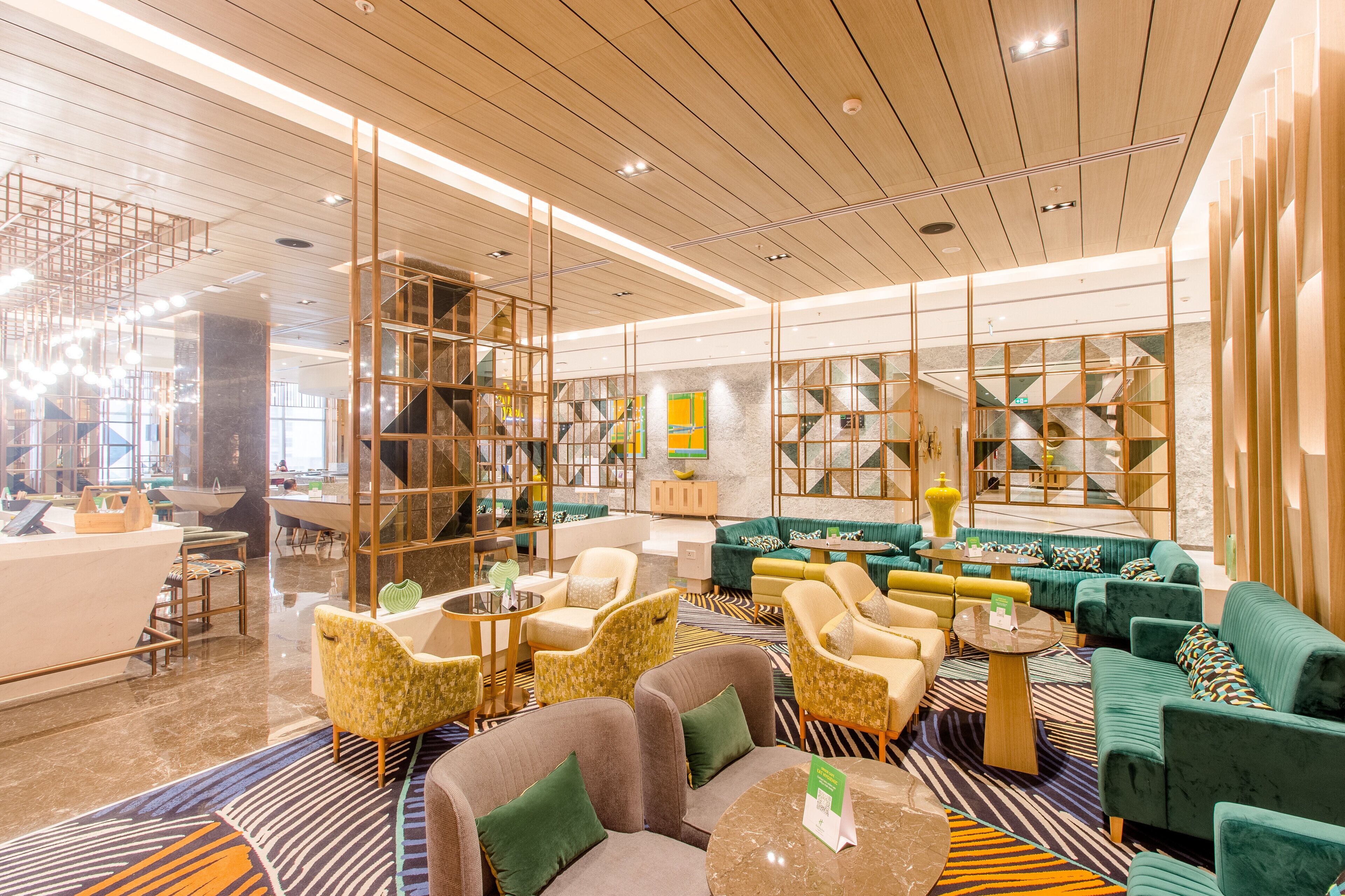 Een moderne hotellobby met diverse zithoeken, een receptiebalie en een trap.