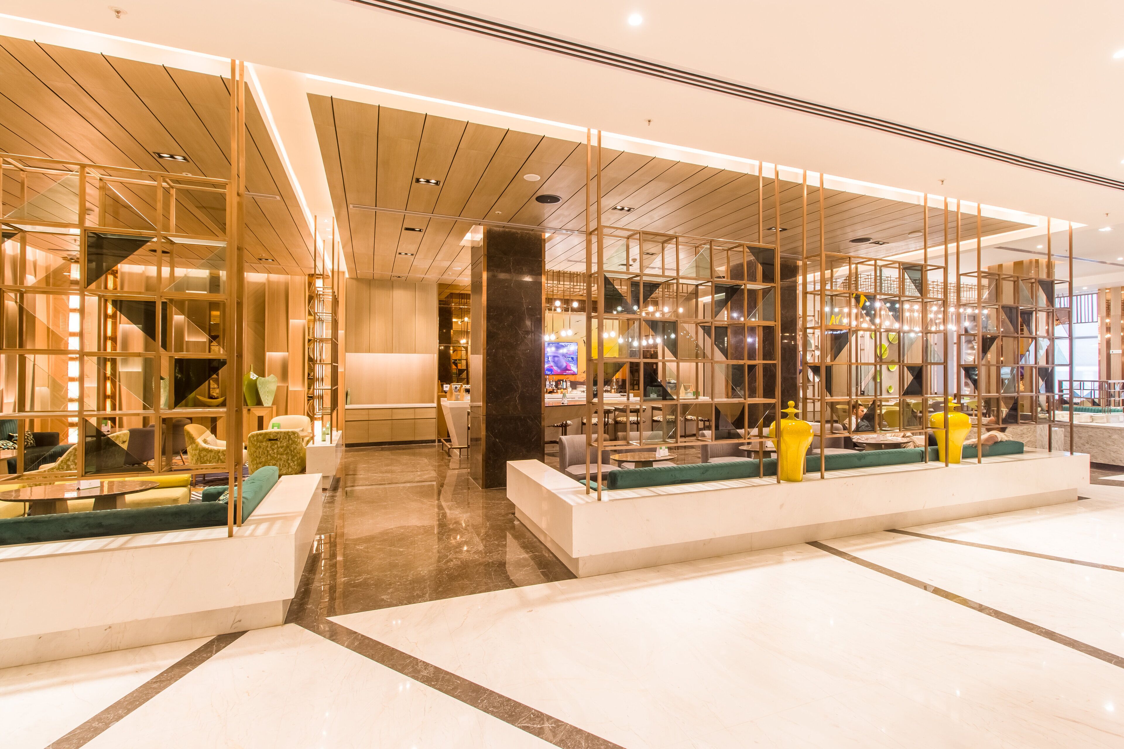 A modern hotel lobby with glass partitions, seating areas, and a central staircase.