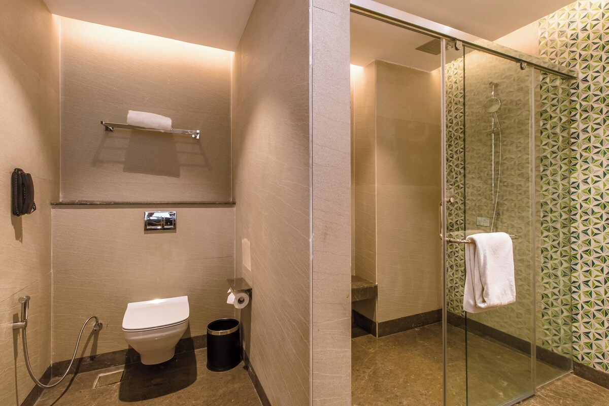 A modern bathroom with a toilet, bidet, and glass shower enclosure.