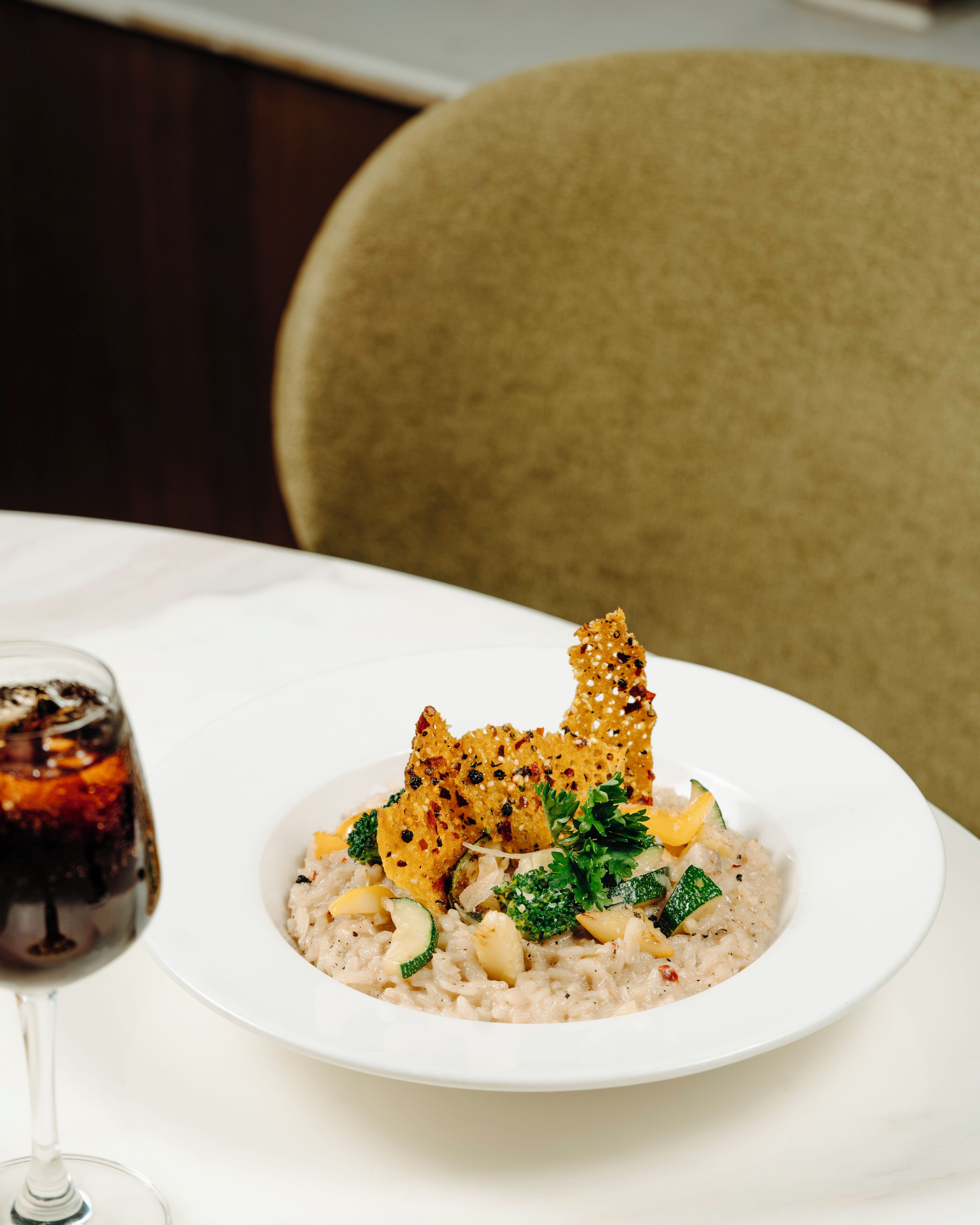 A plate of food with a glass of red wine on a white table.