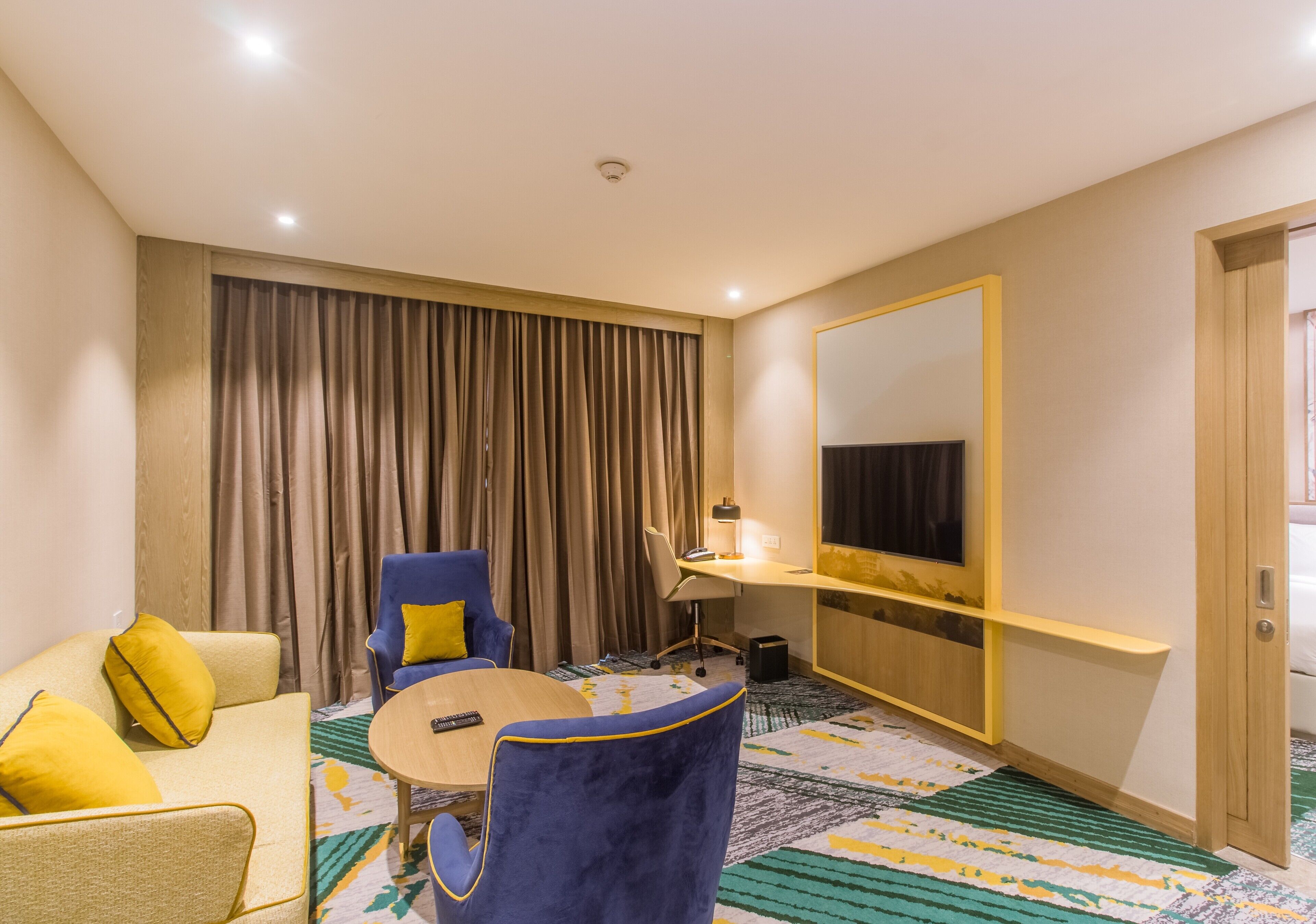 Ein Hotelzimmer mit einer Couch, einem Sessel, einem runden Tisch und einem großen Spiegel.