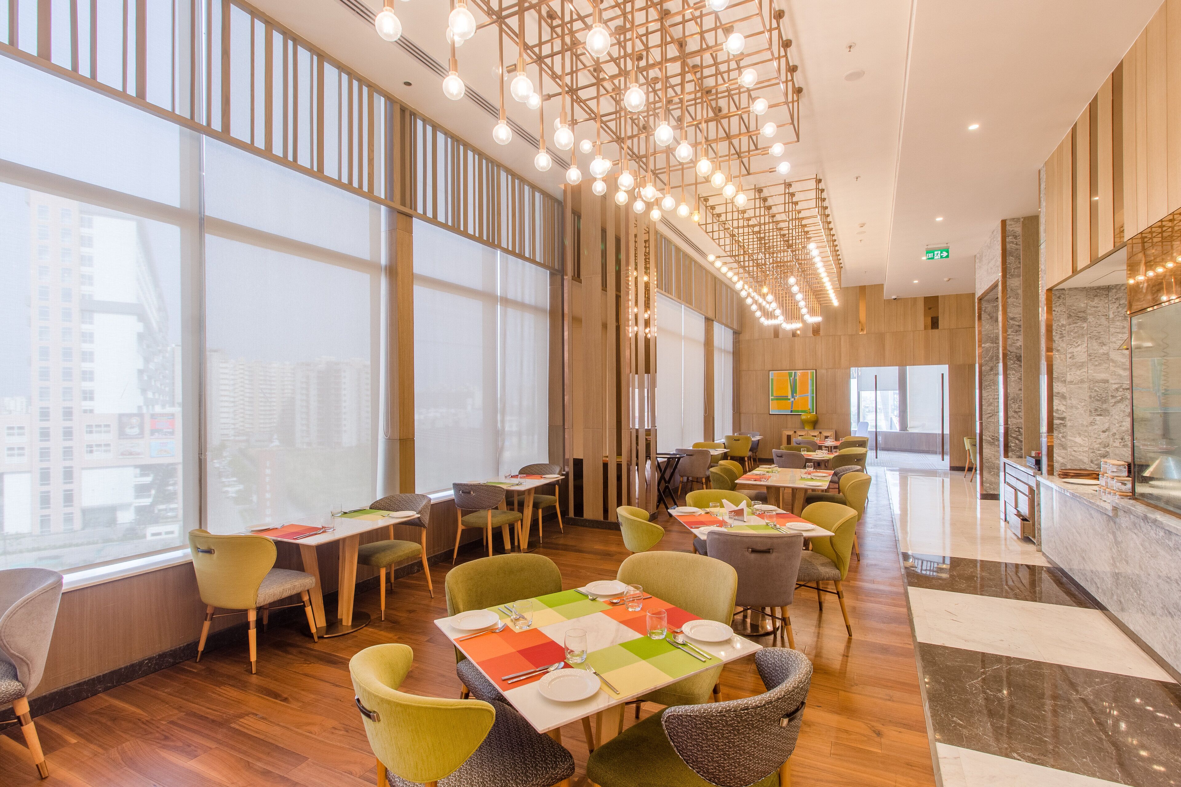 A modern restaurant with high ceilings, large windows, and a variety of seating arrangements.