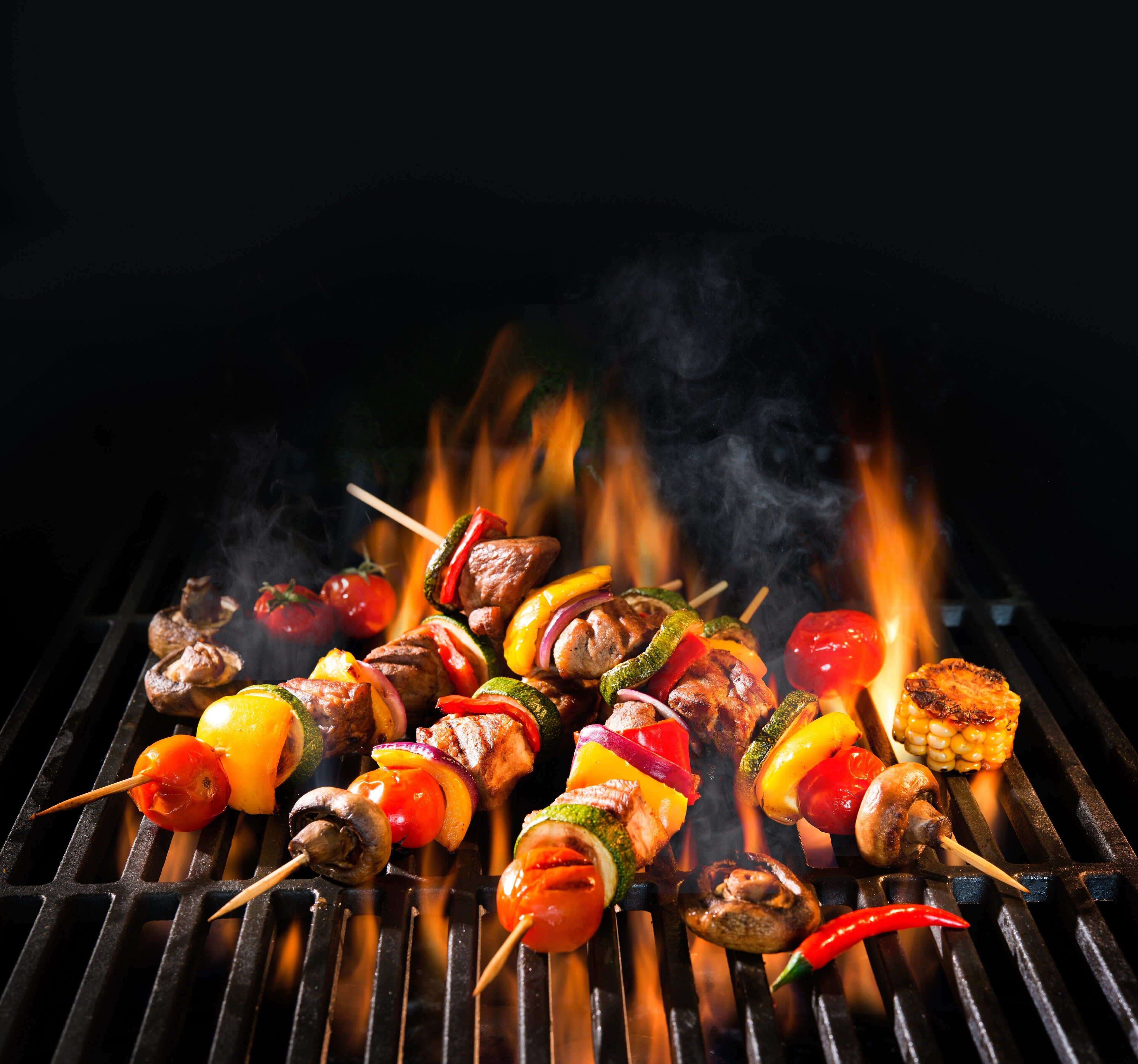 Una parrilla con diversos pinchos de carne y verduras.