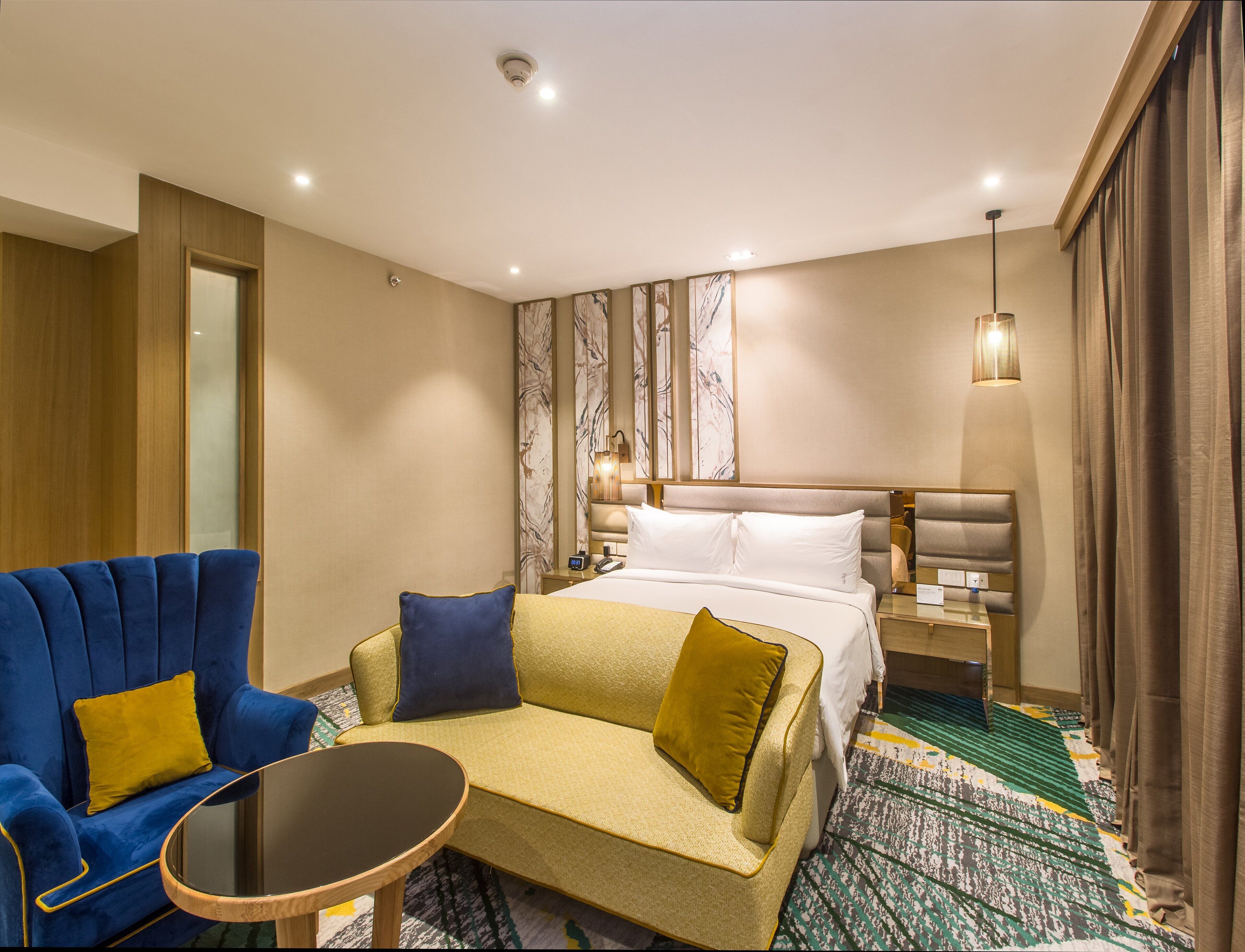 Une chambre d’hôtel avec un lit, un canapé, une petite table et une table de chevet.