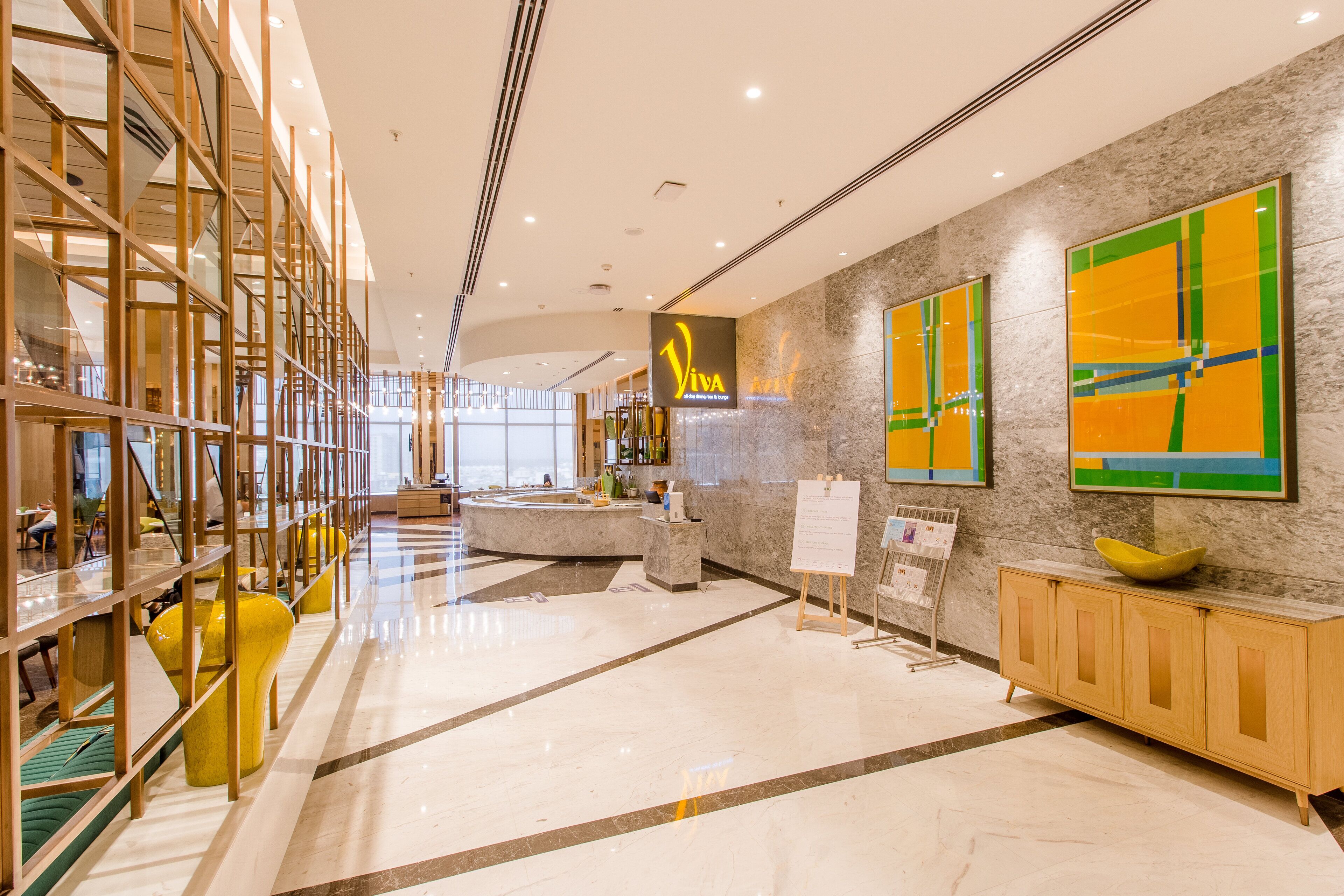 A modern lobby with a marble floor, a reception desk, and a yellow sofa.