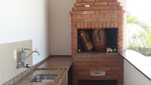 A kitchen with a brick oven, a sink, and a window overlooking greenery. - Country house in a gated community in Itupeva. <br> (Itupeva)