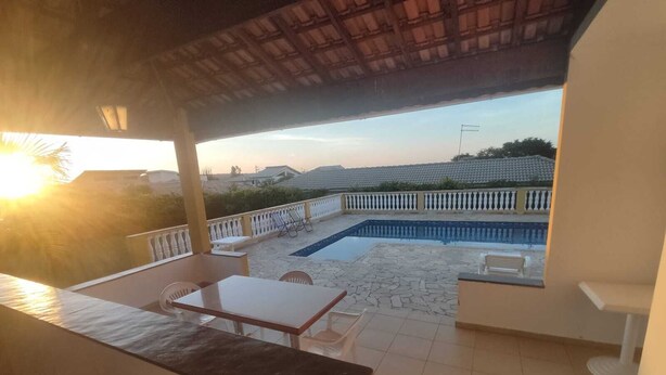 A balcony with a pool, white furniture, and a view of the surrounding area. - Country house in a gated community in Itupeva. <br> (Itupeva)