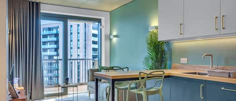 A modern kitchen with a large window, a dining area with bar stools, and a view of a building outside.