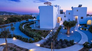 A modern white building with a curved pathway, a tree, and a view of the landscape.