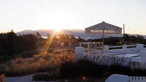 A beachside setting with a white gazebo, a pathway, and a view of the sunset over the sea.