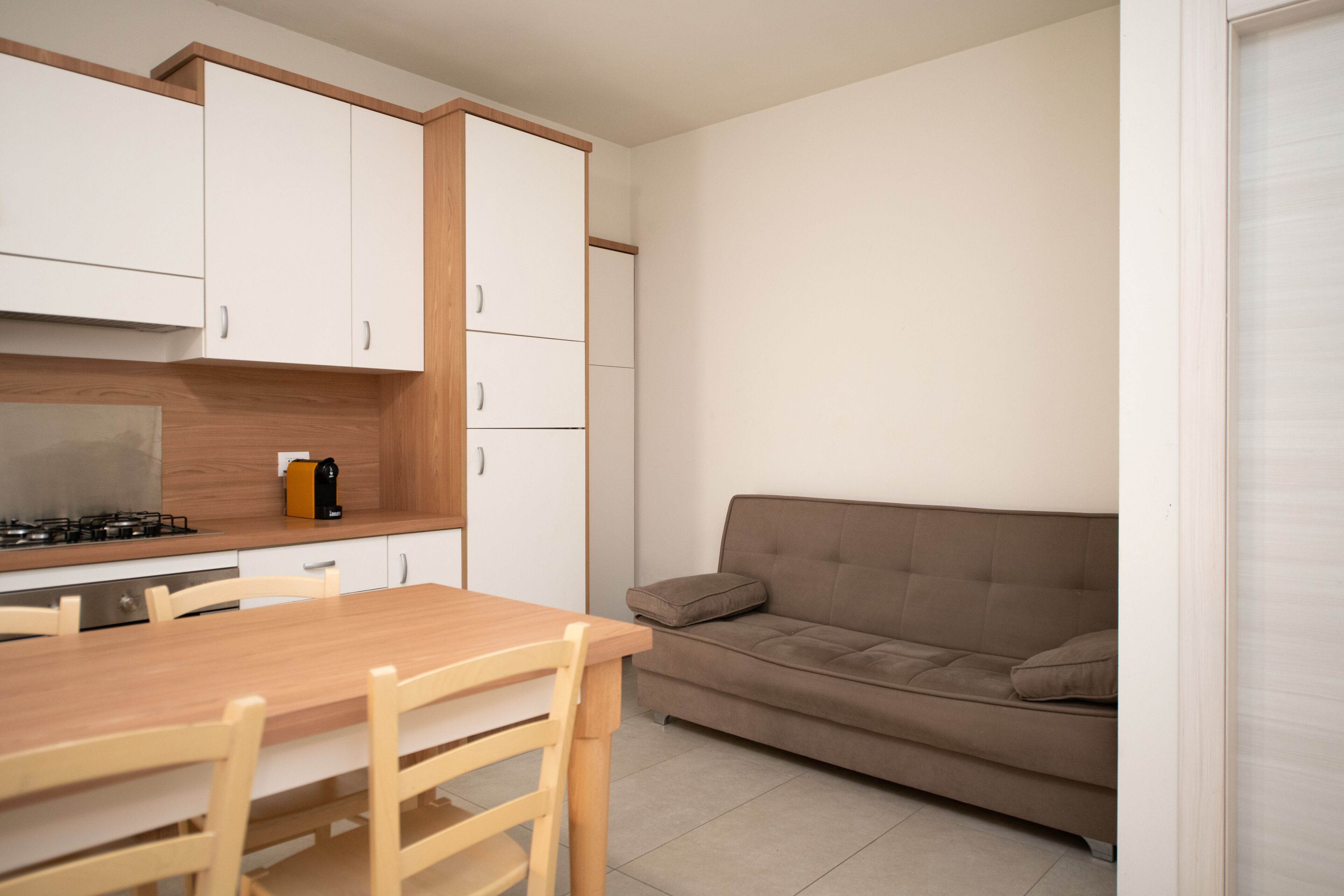 Un espacio habitable compacto con kitchenette, una mesa de comedor con sillas y un sofá.