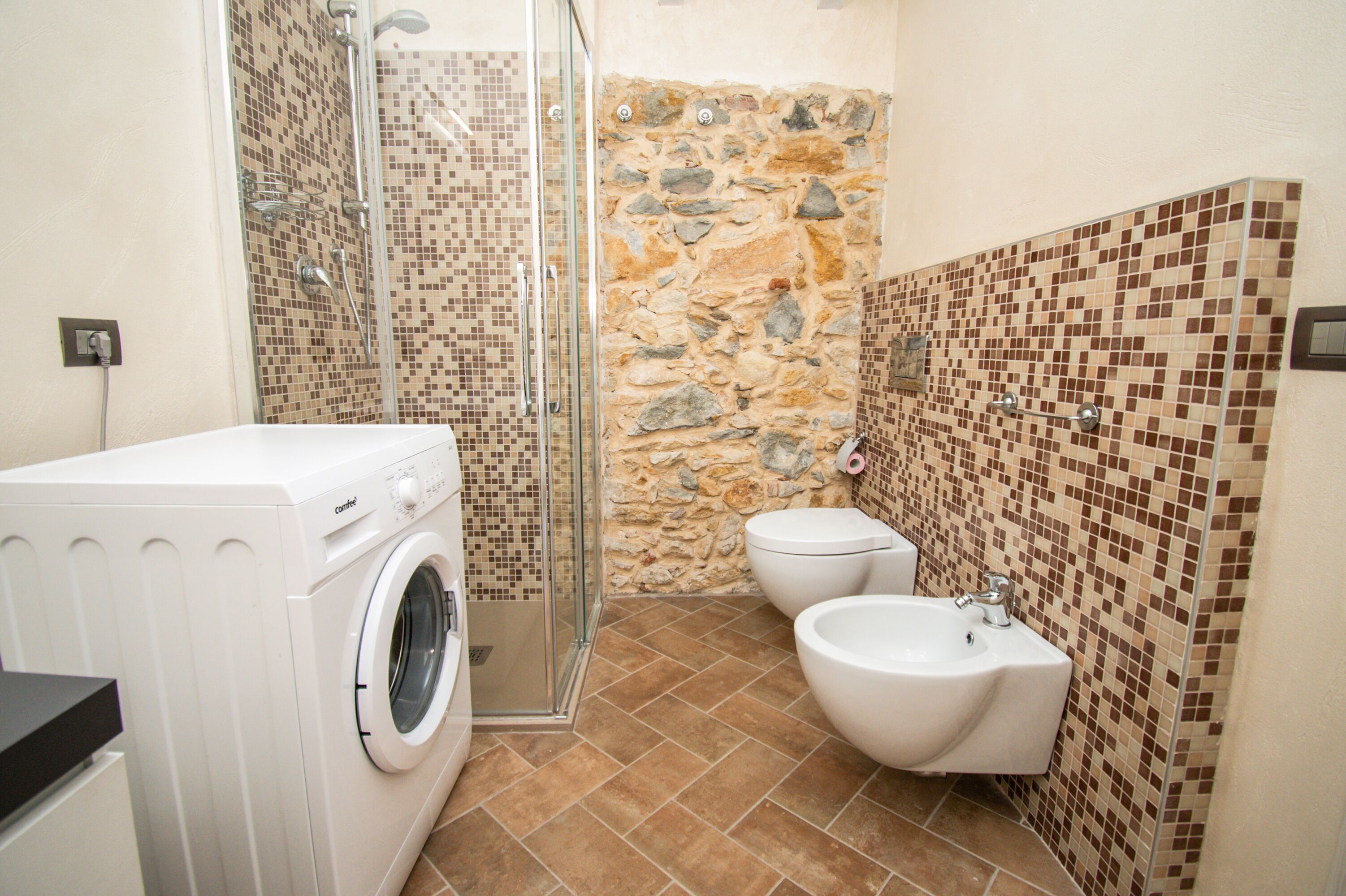 Un bany amb rentadora, dutxa envidriada, vàter i bidet.