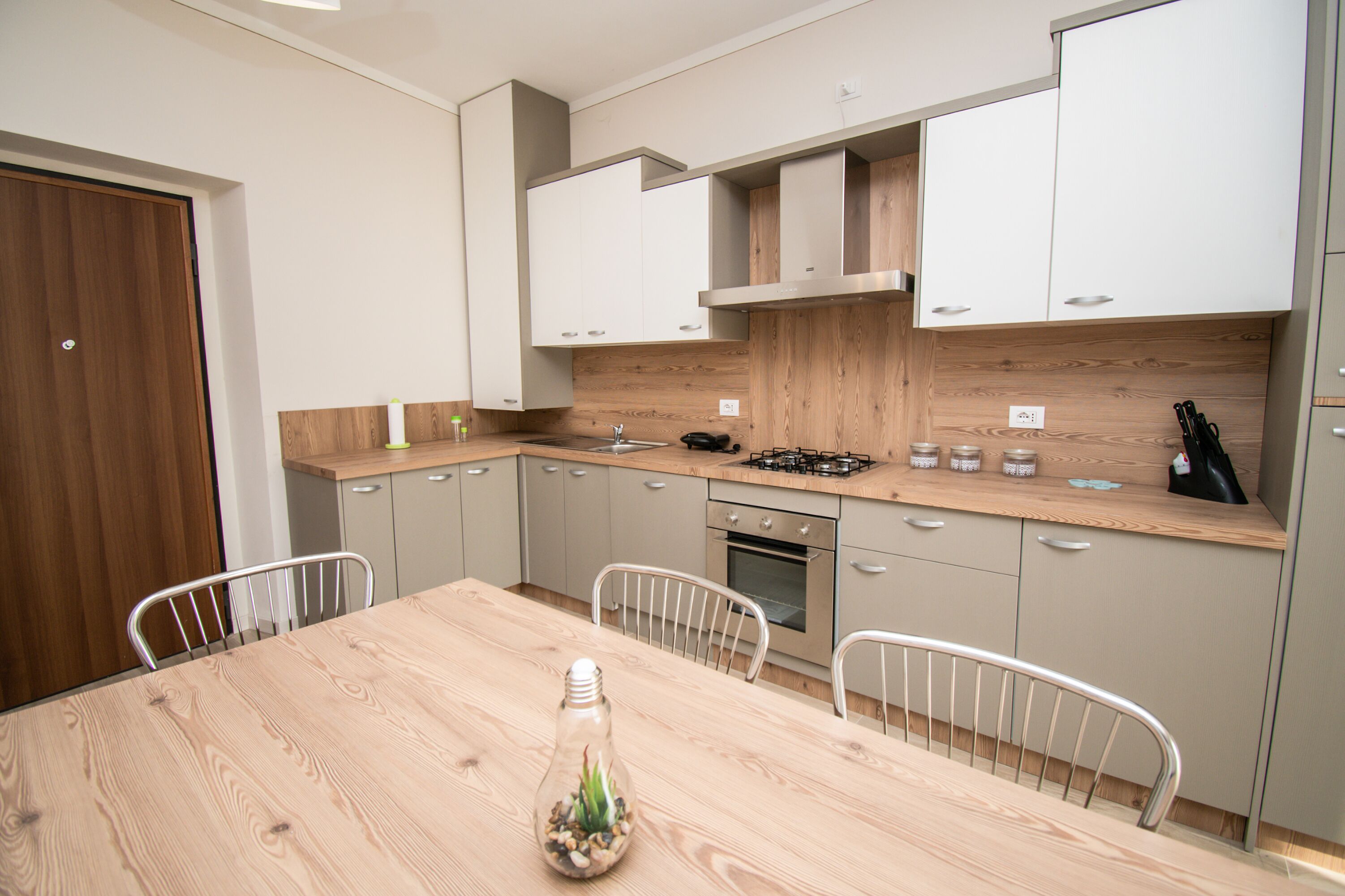 A modern kitchen with wooden cabinets, a gas stove, and a dining table with chairs.