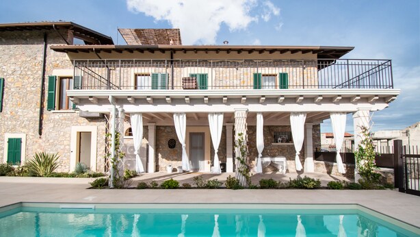 Un edificio de piedra de dos pisos con una piscina delantera.