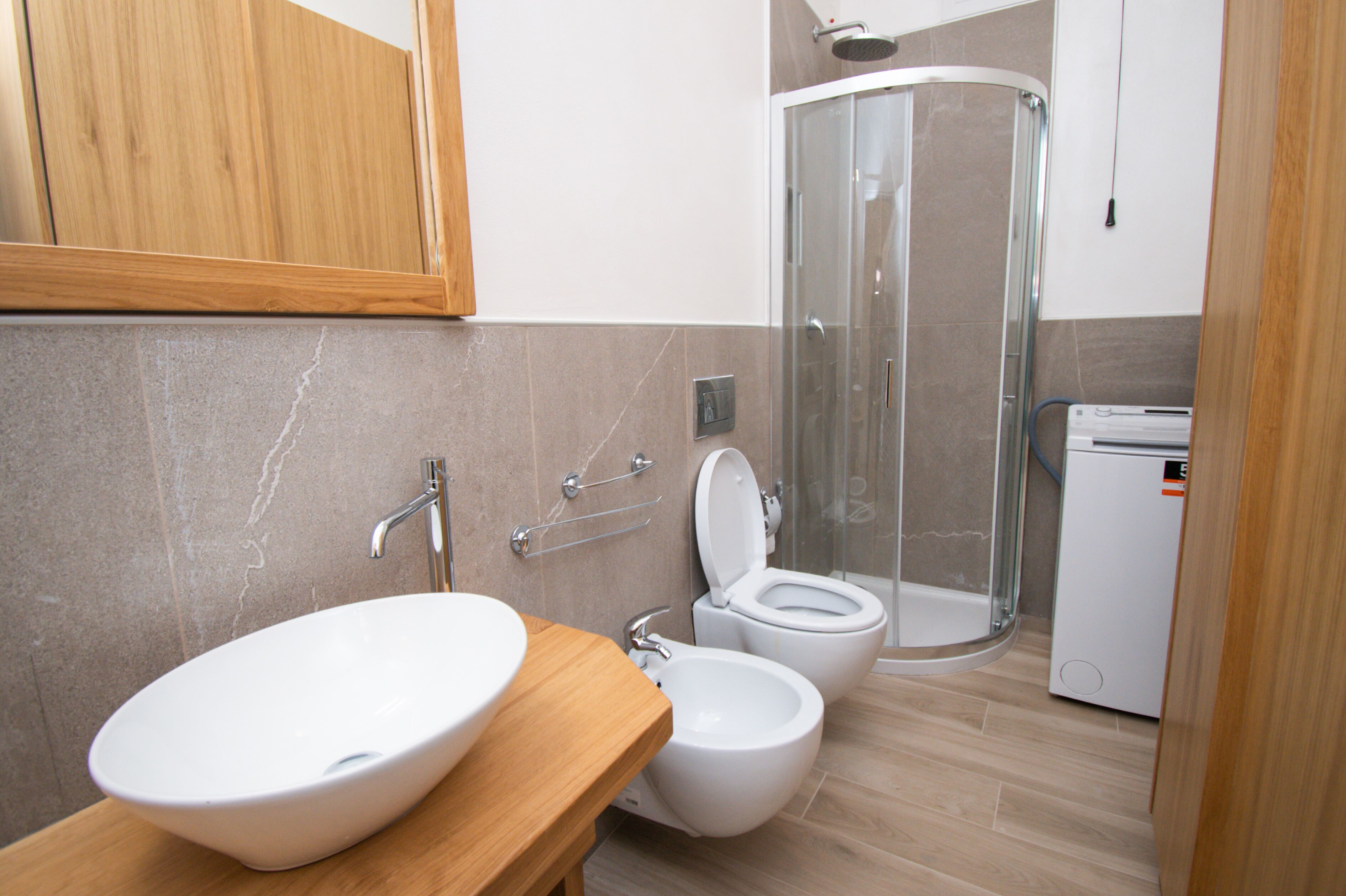 Une salle de bain équipée d’un lavabo, de deux toilettes, d’une douche et d’un petit radiateur.